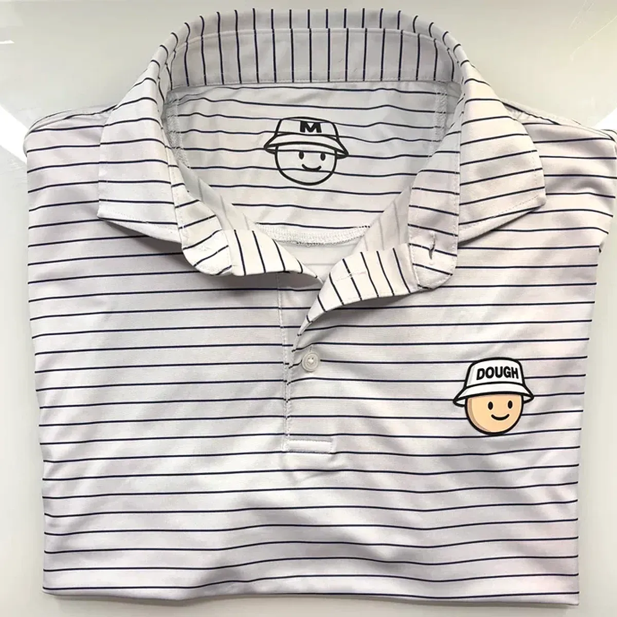 White pinstripe performance golf polo with the embroidered Doughboy dough-face crest at the chest.