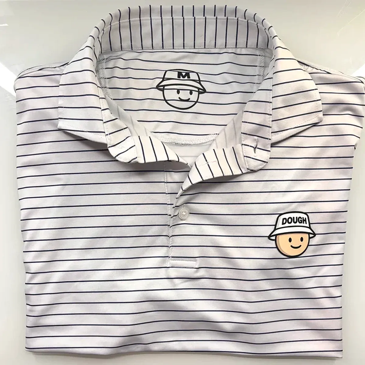White pinstripe performance golf polo with the embroidered Doughboy dough-face crest at the chest.